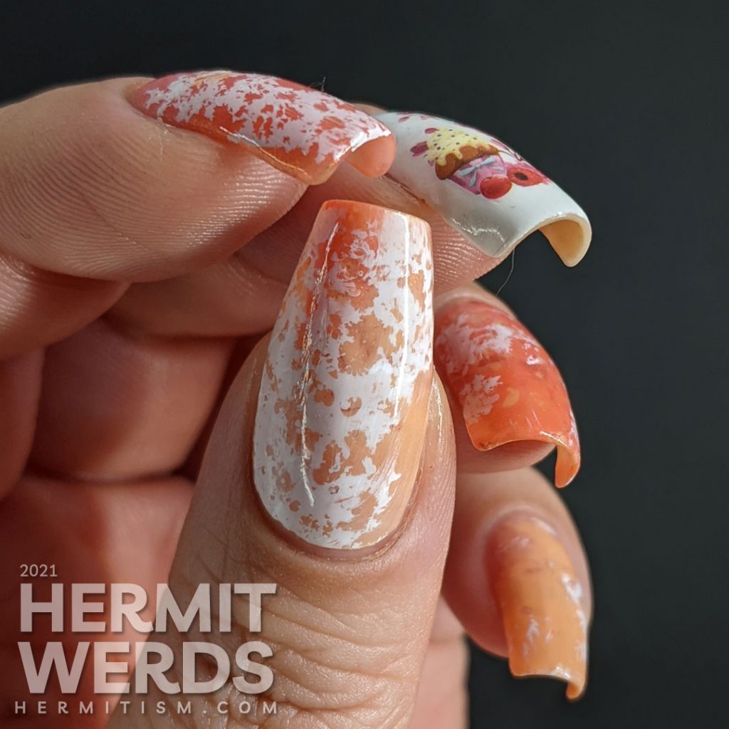 A cupcake nail art with a cupcake water decal accent nail and creamsicle-like water spotted nails in white, orange, and coral.