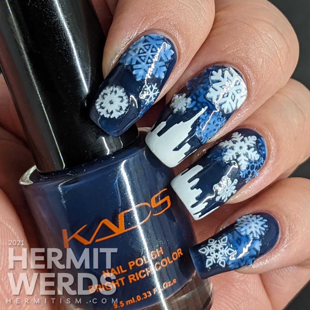 A pond mani with glow in the dark snowflake stickers and a white panoramic cityscape using a dark blue jelly polish.