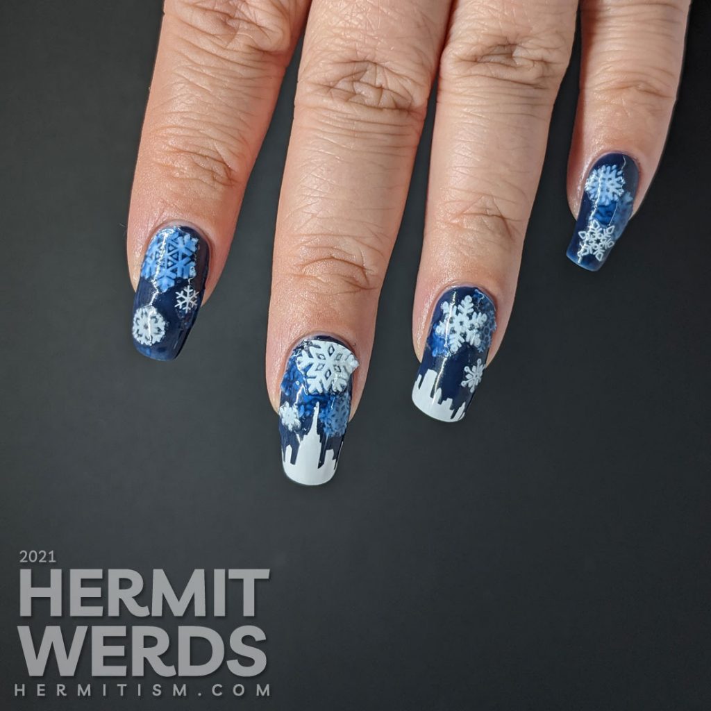 A pond mani with glow in the dark snowflake stickers and a white panoramic cityscape using a dark blue jelly polish.