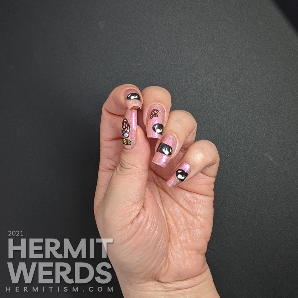 A pink to gold multichrome with holographic nail art featuring Nintendo's Mario dodging multiple Bullet Bills.