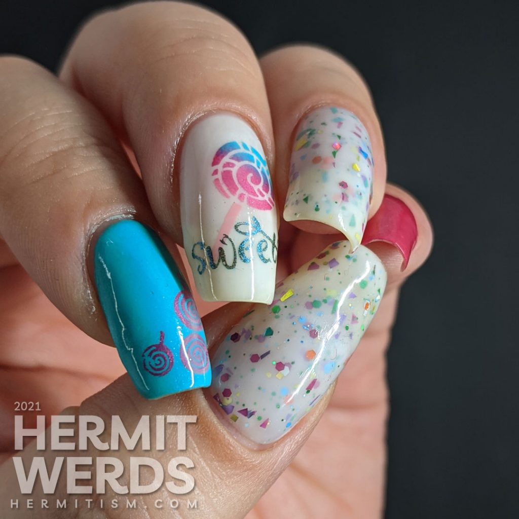 Cute candy nail art in blue, pink, and white with lollipop stamping decals, the word "sweet", and a rainbow crelly.