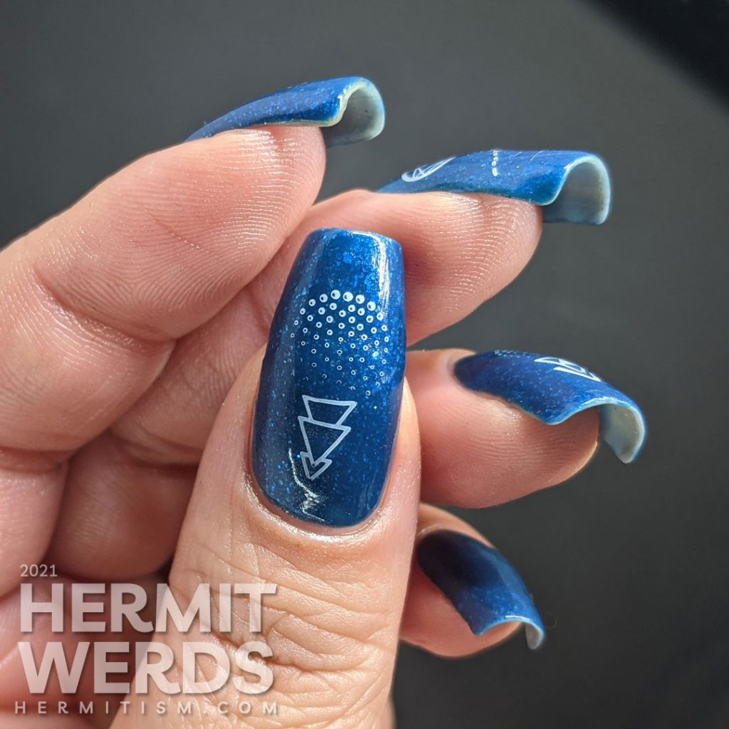 A medium blue polish with glitters and micro flakies with geometrically stylized cotton candy stamped on top.