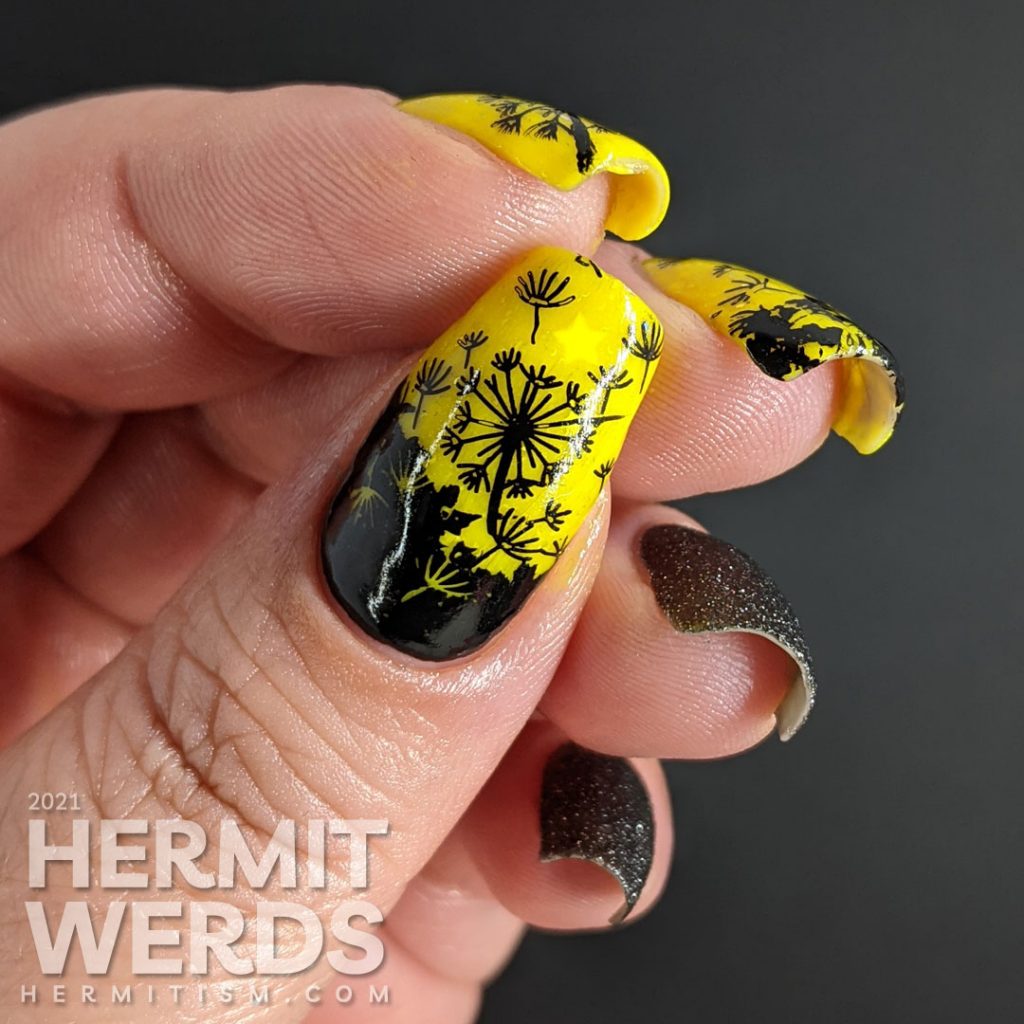 A neon yellow crelly and black texture polish manicure with negative space black dandelions stamped on top. Glows in the dark.