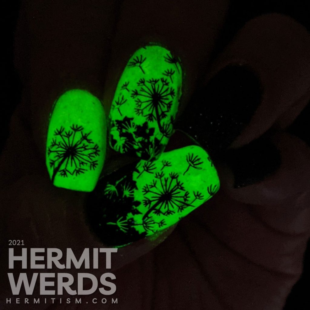 A neon yellow crelly and black texture polish manicure with negative space black dandelions stamped on top. Glows in the dark.