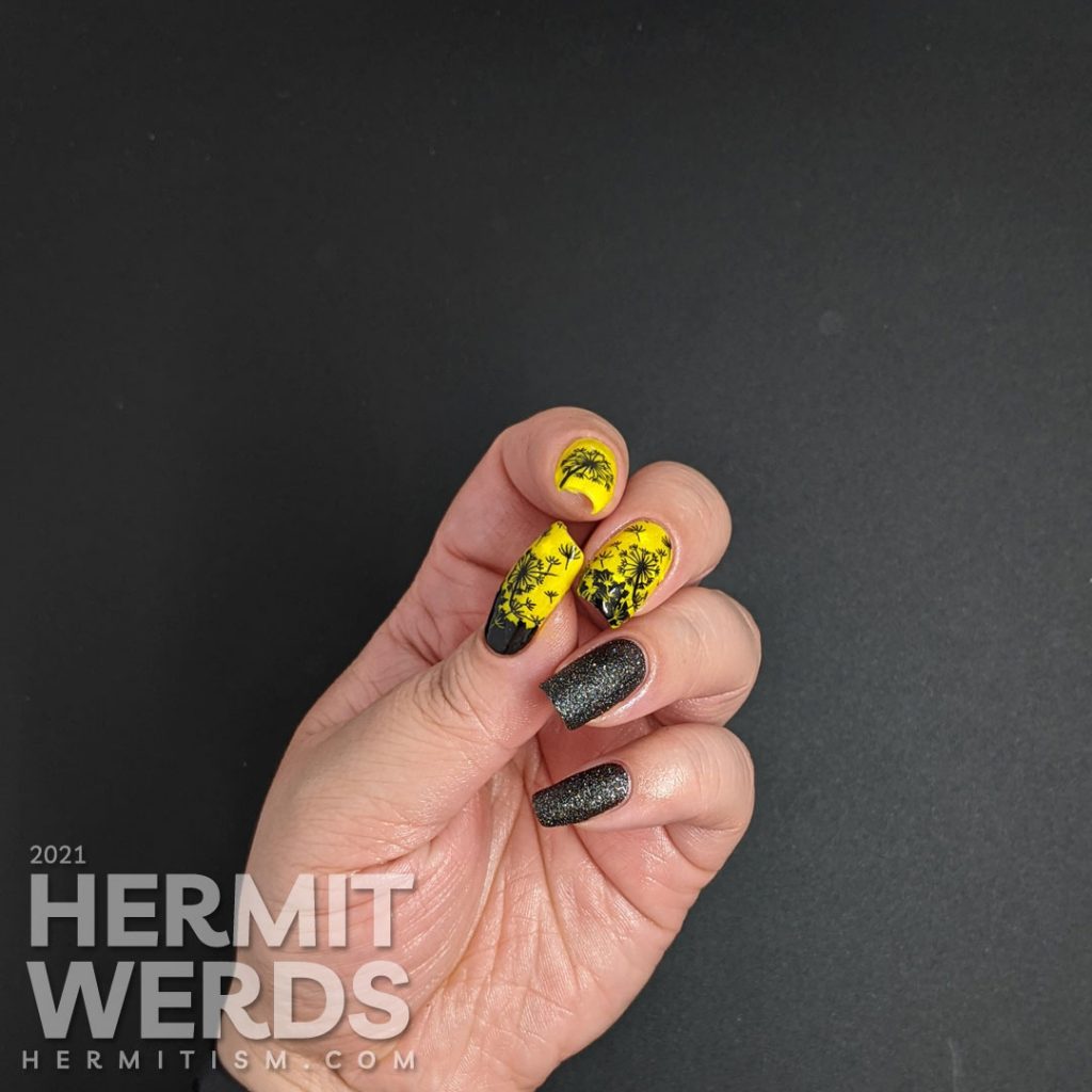 A neon yellow crelly and black texture polish manicure with negative space black dandelions stamped on top. Glows in the dark.