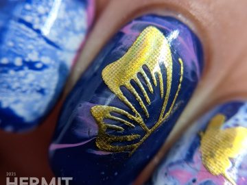 A fluid art nail art decorated with holographic gold butterfly stickers in blue, blurple, lavender, and white.