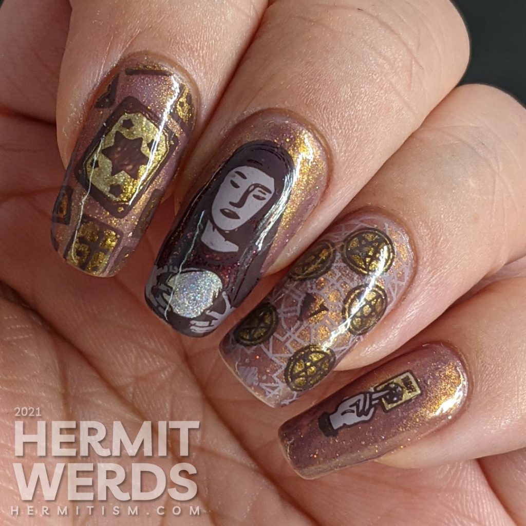 A mauve and gold magnetic nail art with tarot cards, the five of pentacles, all-seeing eye, and a fortune teller and her glass ball.