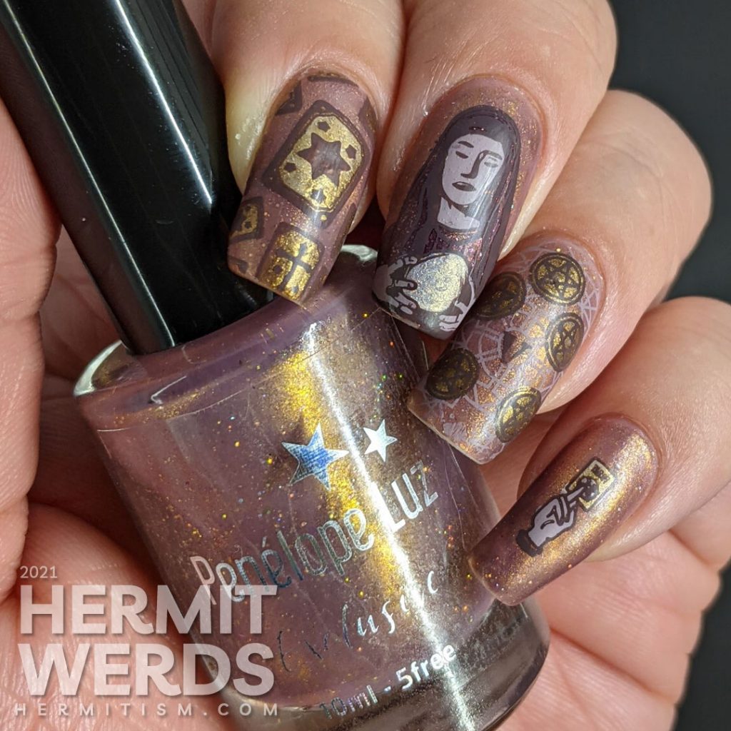 A mauve and gold magnetic nail art with tarot cards, the five of pentacles, all-seeing eye, and a fortune teller and her crystal ball.