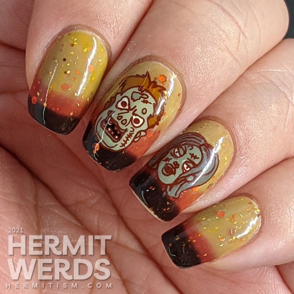 Zombie nail art with cartoon zombie head stamping decals and on a mustard/orange/brown tri-thermal base with orange and gold glitters.