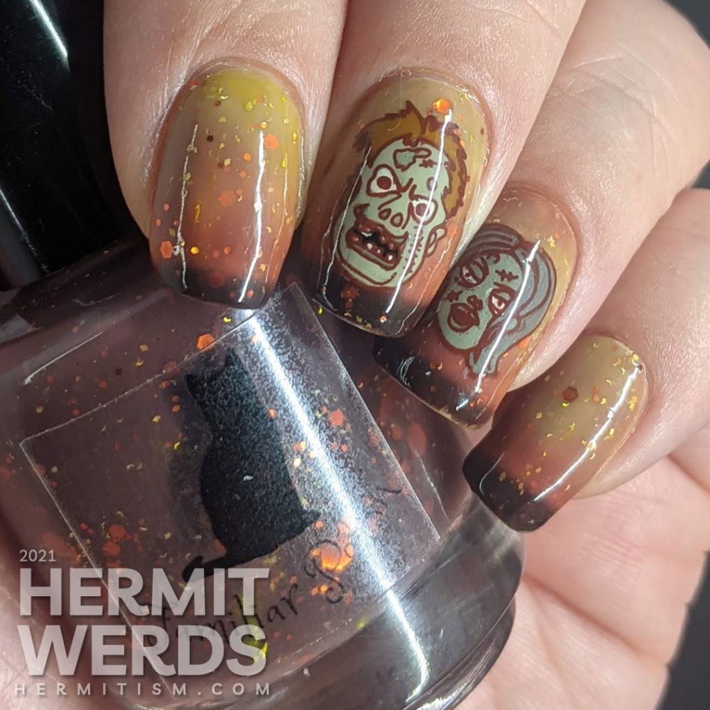 Zombie nail art with cartoon zombie head stamping decals and on a mustard/orange/brown tri-thermal base with orange and gold glitters.