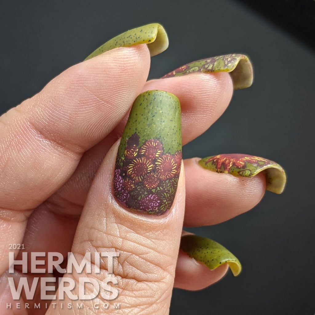 Autumn-esque nail art of yellow, orange, and brown sunflower stamping decals on an olive green speckled nail polish base.