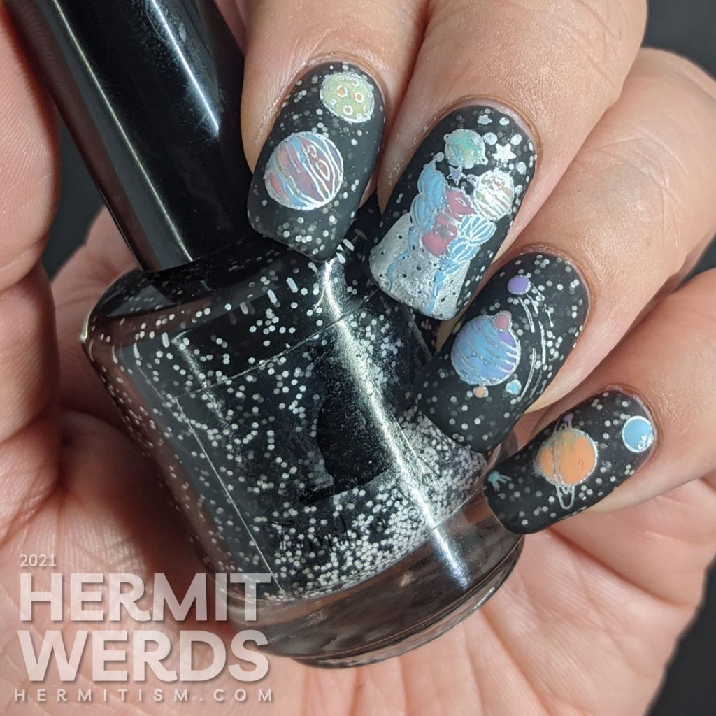 An outer space mani, with a field of stars created by white glitter in a black jelly and colorful stamping images of planets and a planet-headed lady.