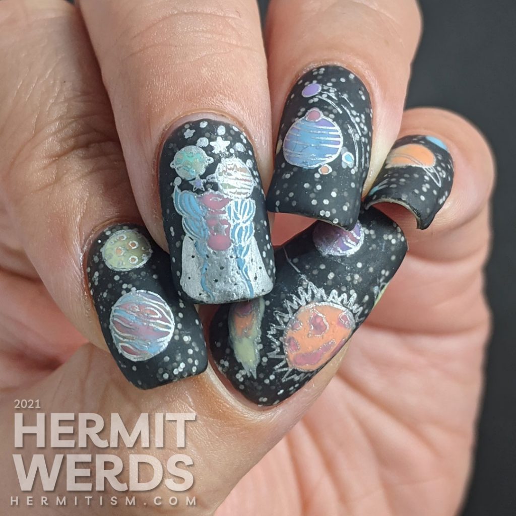 An outer space mani, with a field of stars created by white glitter in a black jelly and colorful stamping images of planets and a planet-headed lady.