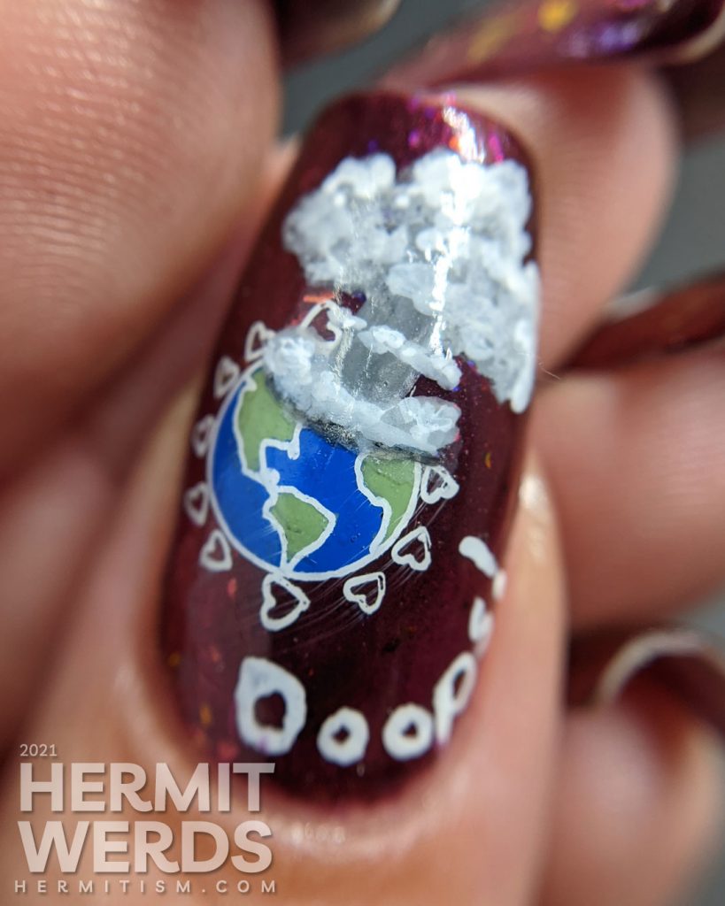 A plum flakie filled polish with earth-loving stamping images on top and a surprise nuclear explosion blowing up the planet. Oops!