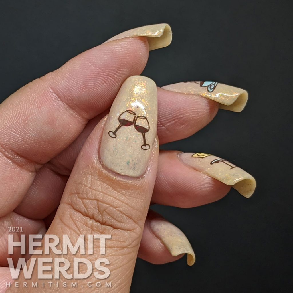 French nail art on a flakie-filled cream crelly with stamping decals of delicious French food like wine, croissants, and french press coffee.