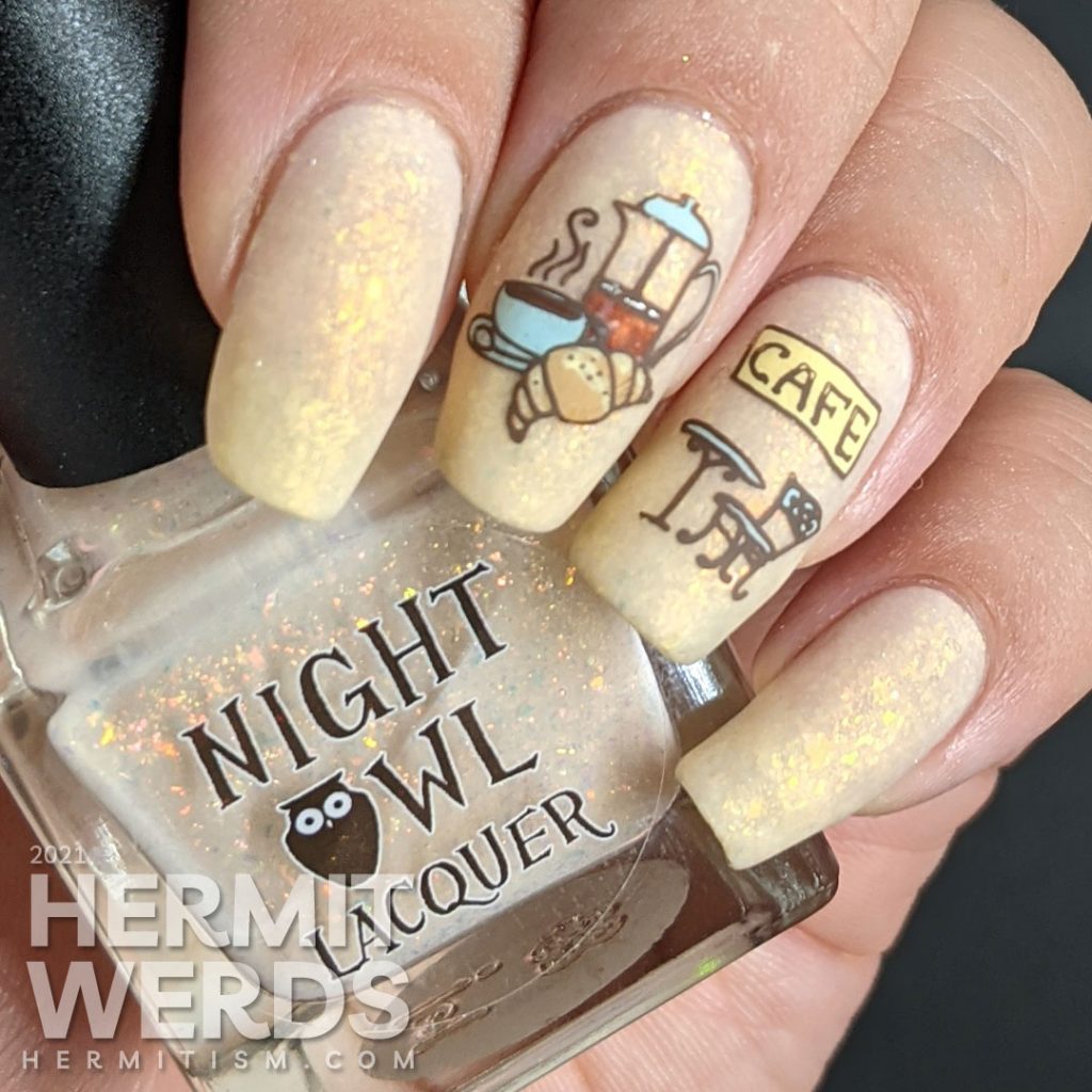 French nail art on a flakie-filled cream crelly with stamping decals of delicious French food like wine, croissants, and french press coffee.