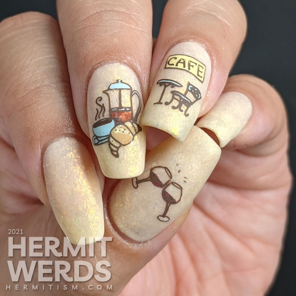 French nail art on a flakie-filled cream crelly with stamping decals of delicious French food like wine, croissants, and french press coffee.