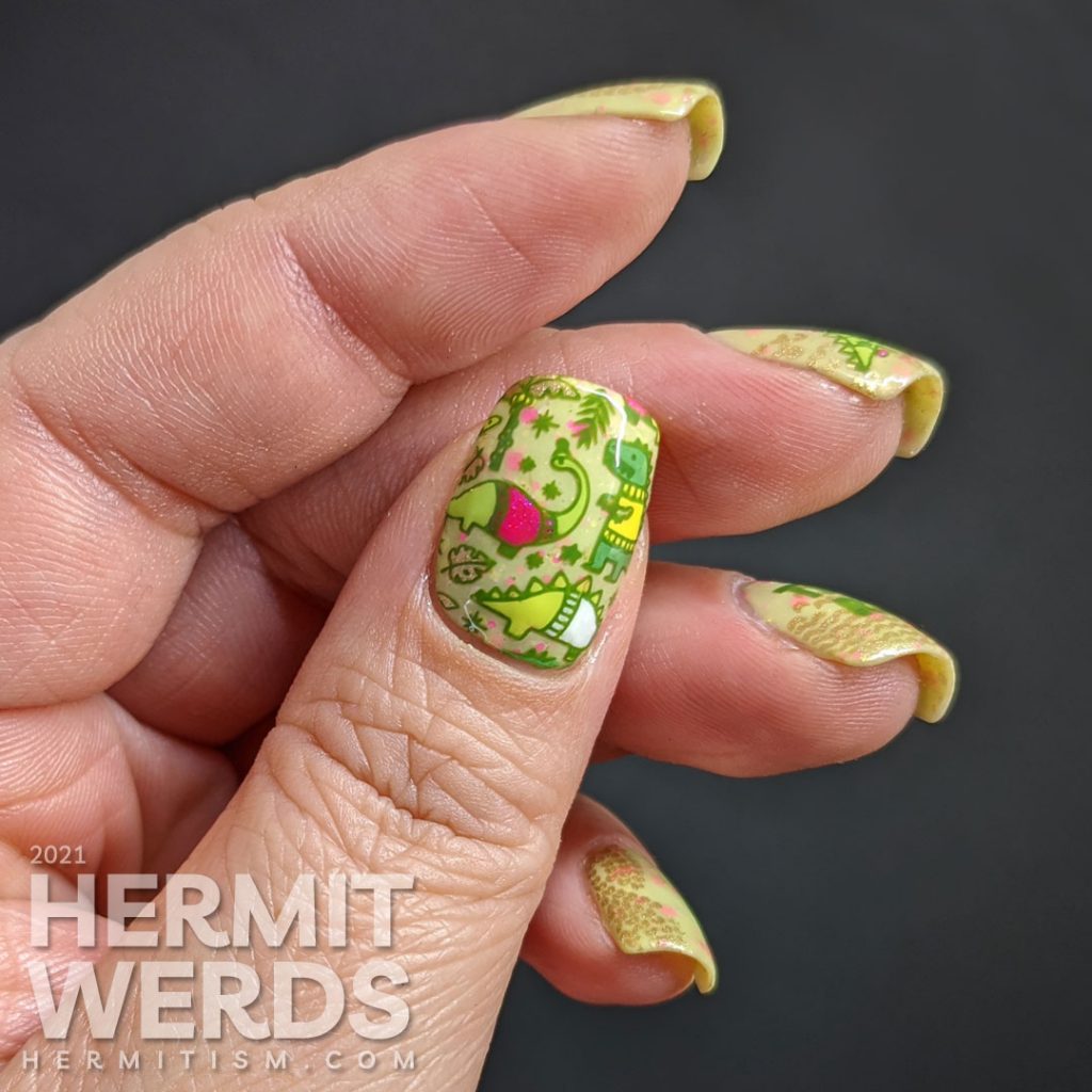 Christmas nail art with stamping decals of Tree Rex & dinosaurs in cozy sweaters in neon pink, green, yellow, and white on a green crelly.