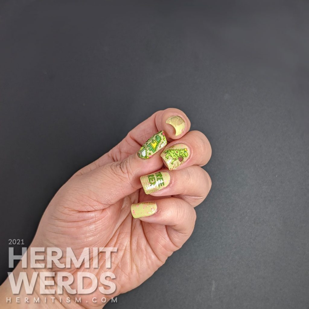 Christmas nail art with stamping decals of Tree Rex & dinosaurs in cozy sweaters in neon pink, green, yellow, and white on a green crelly.