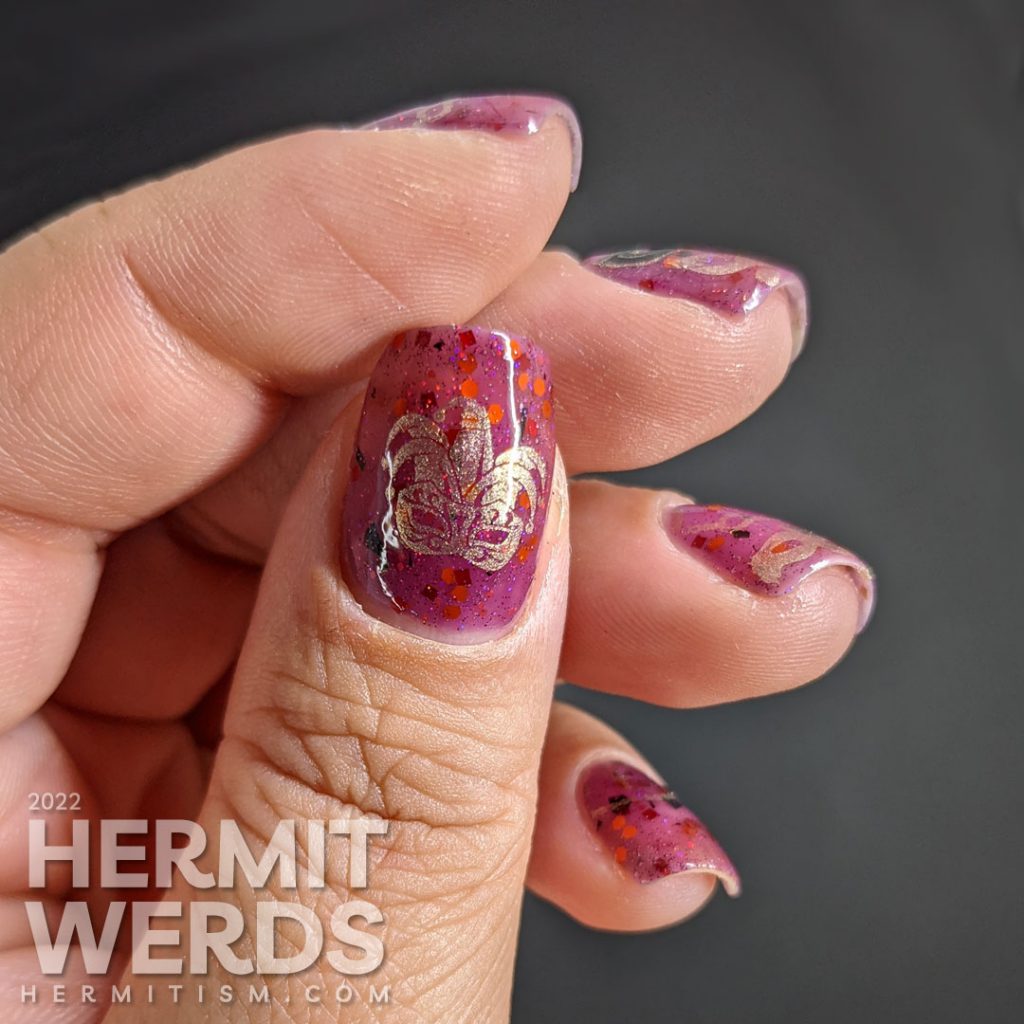 A plum-colored nail art celebrating Carnival season in Italy with golden strings of beads and many different masks.