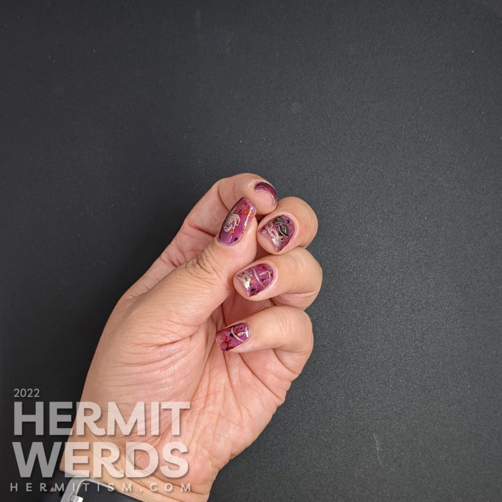 A plum-colored nail art celebrating Carnival season in Italy with golden strings of beads and many different masks.