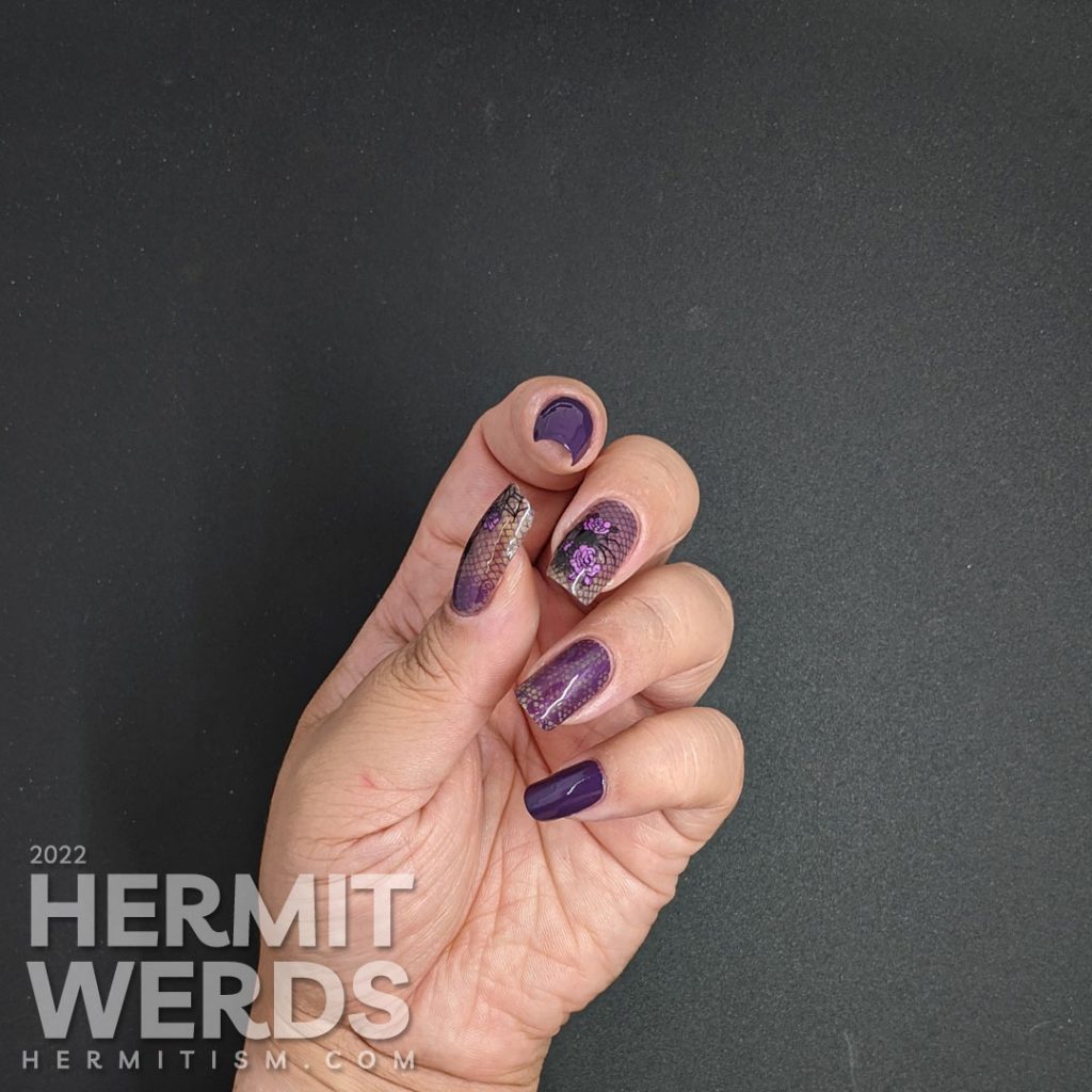 A gothic purple spider mani with lacy purple accent nails decorated with rose, spider, and lace stamping decals.