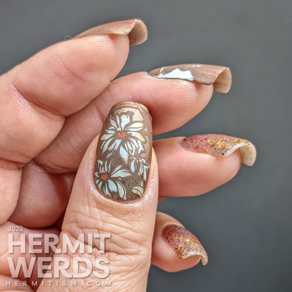 A soft, golden brown art nouveau nail art with a beautiful art nouveau woman, florals, and accompanying sparkly accent nails.