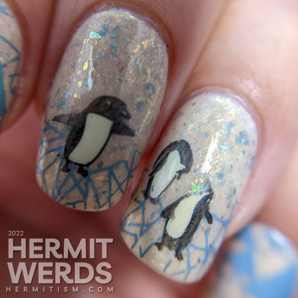 Soft penguin nail art with metallic black stamping images of fanciful penguins and grey-blue geometric ice patterns.