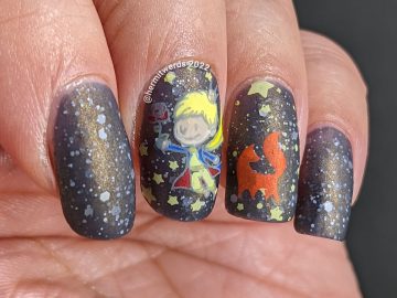 An outer space Le Petit Prince nail art with stamping decals of the Prince, fox, and rose on a deep navy crelly with white glitter stars.