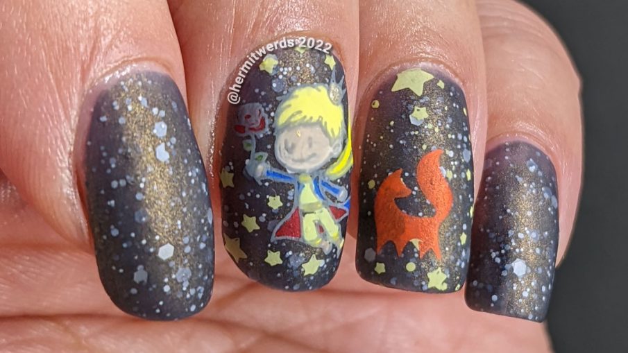 An outer space Le Petit Prince nail art with stamping decals of the Prince, fox, and rose on a deep navy crelly with white glitter stars.
