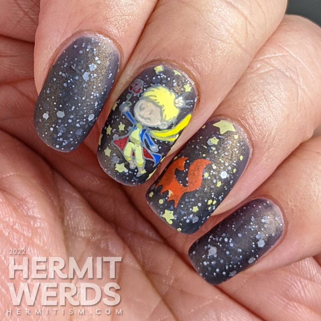 An outer space Le Petit Prince nail art with stamping decals of the Prince, fox, and rose on a deep navy crelly with white glitter stars.