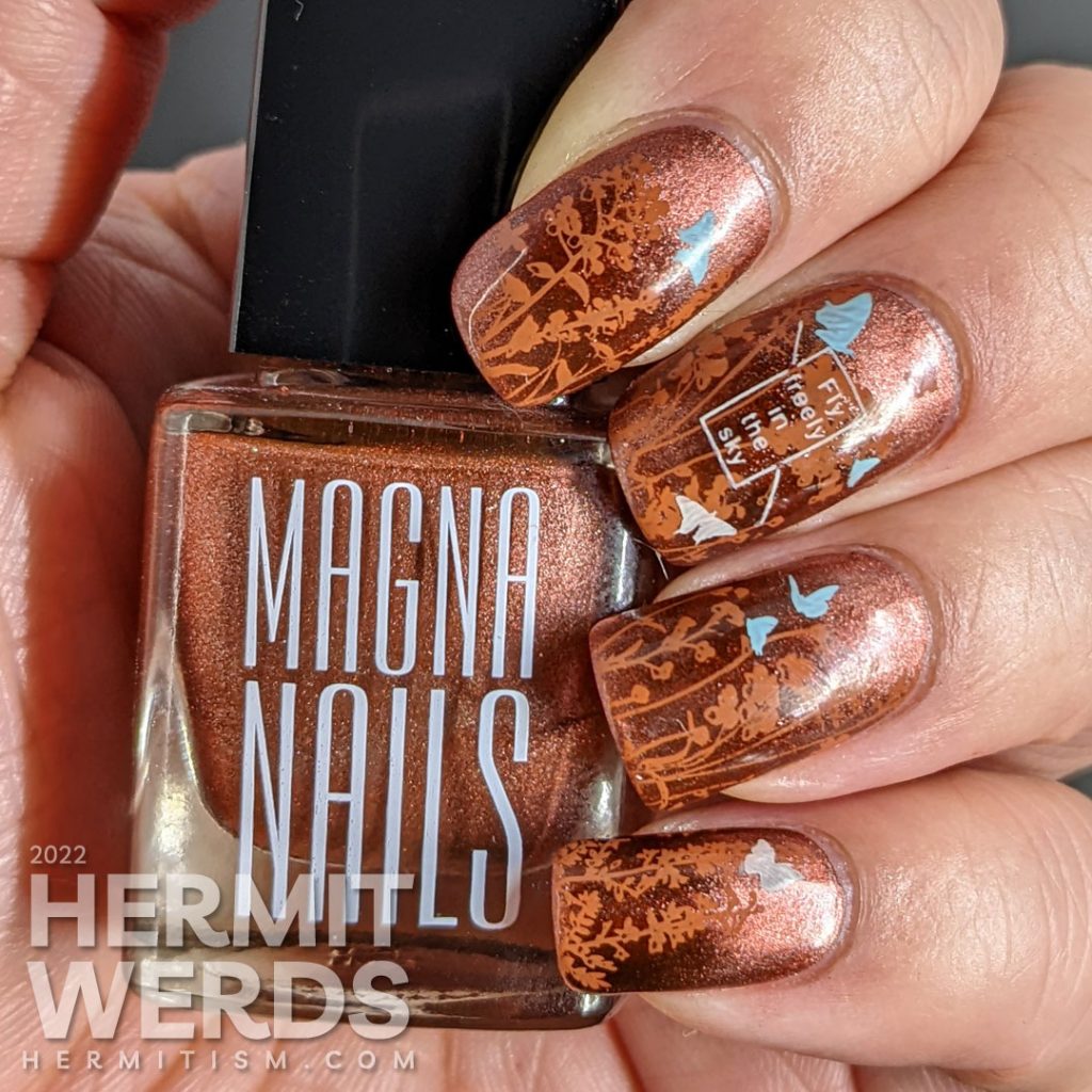 A coppery-y floral mani with a magnetic copper base and simple stamping images of a floral field and tiny baby blue and white butterflies.