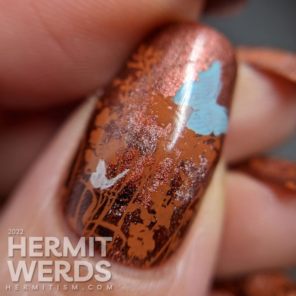 A coppery-y floral mani with a magnetic copper base and simple stamping images of a floral field and tiny baby blue and white butterflies.