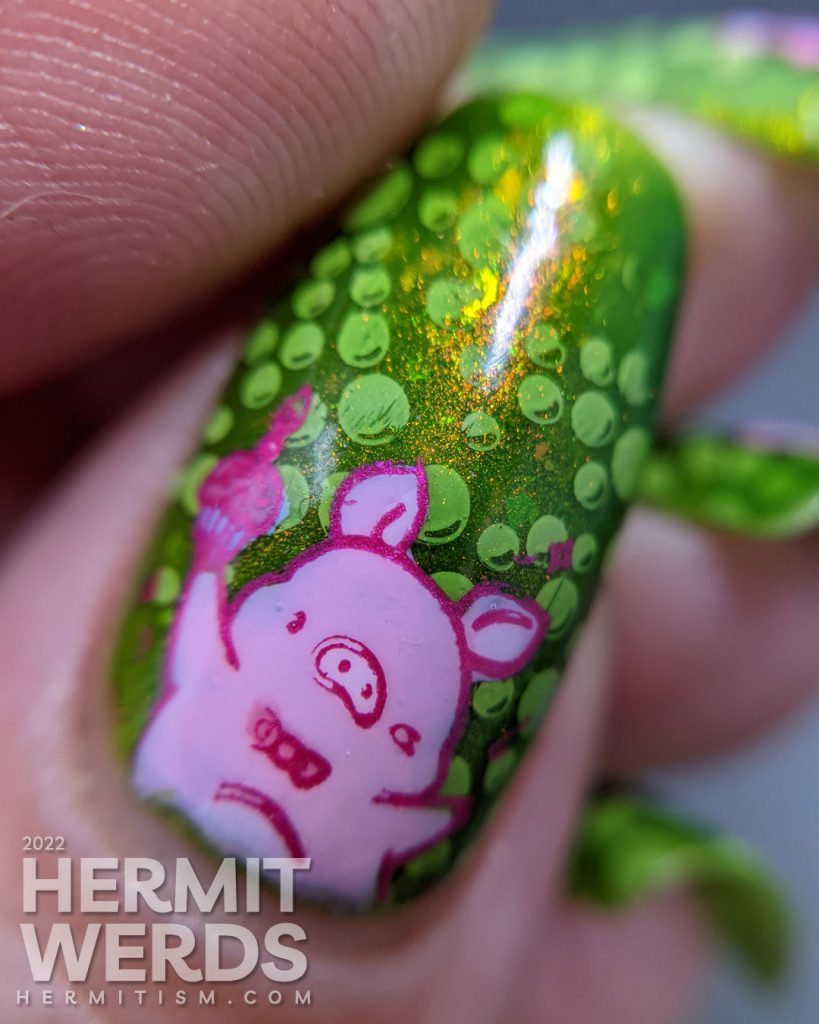 A polka dot pig nail art with party pig reverse stamping decals and polka dots tucked between layers of a bright green jelly polish.