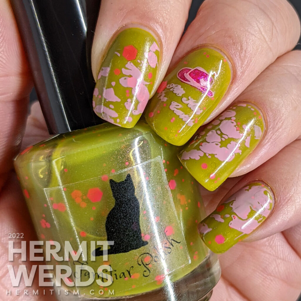 Cowgirl nail art on a green base with pink glitters, pink stamping decals of pink cowhide print, cowboy hat, and cowgirl with a "bang" flag.