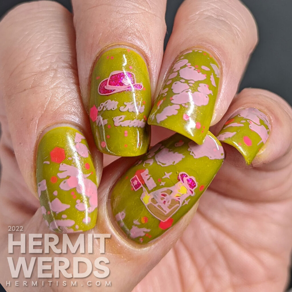 Cowgirl nail art on a green base with pink glitters, pink stamping decals of pink cowhide print, cowboy hat, and cowgirl with a "bang" flag.