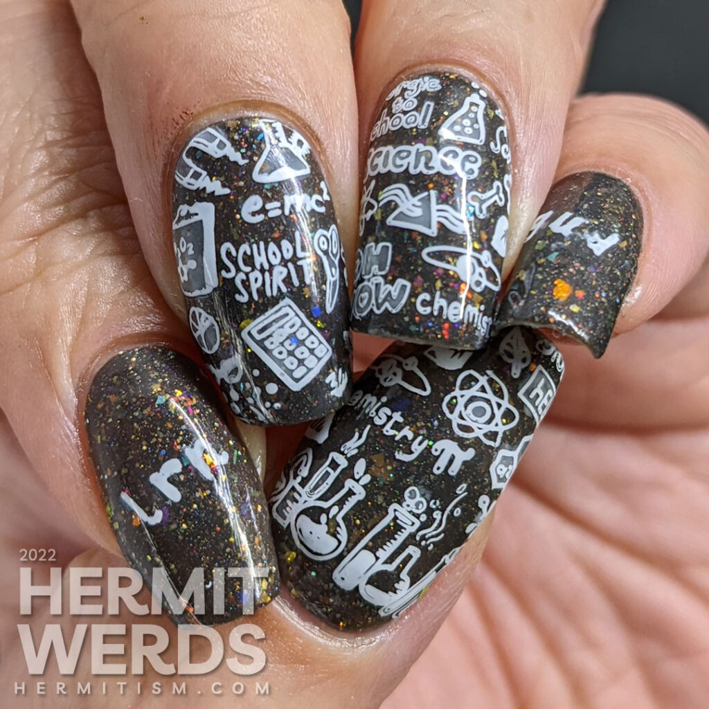 Back to school nail art with chalkboard stamping images about education topics (esp science) on a charcoal rainbow flakie background.