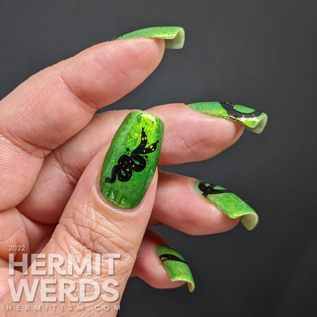 A green glow in the dark nail art with a long snake stamping decal stretched across the nails and a hidden snake-y message.