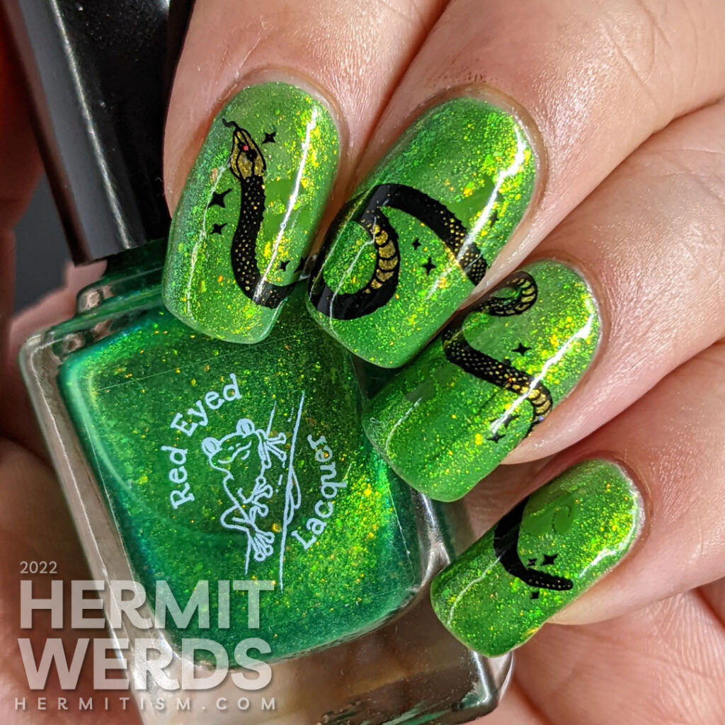 A green glow in the dark nail art with a long snake stamping decal stretched across the nails and a hidden snake-y message.