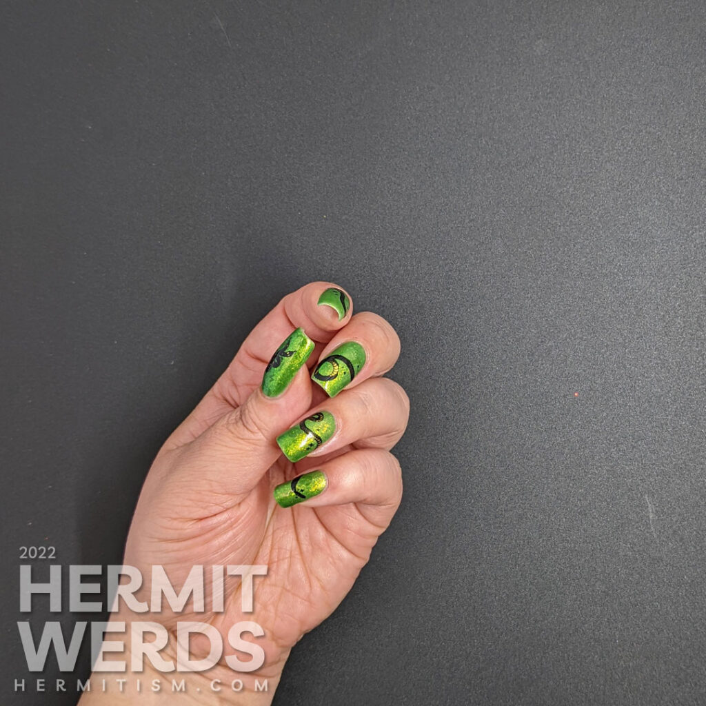 A green glow in the dark nail art with a long snake stamping decal stretched across the nails and a hidden snake-y message.