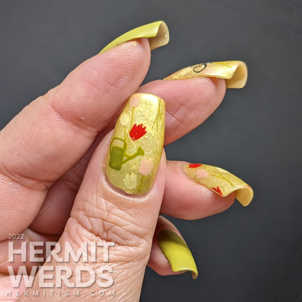 A spring floral mani with yellow, red, and pink tulips and a watering can stamped over a bright green holographic polish.