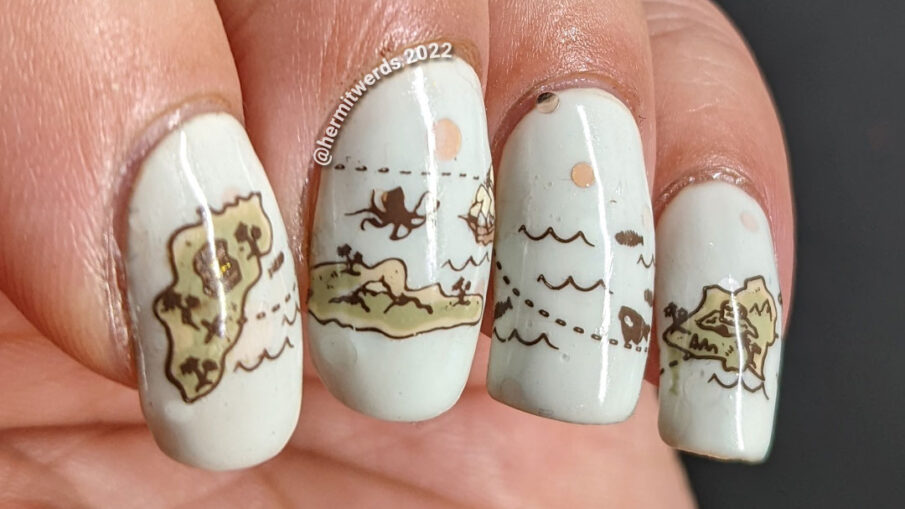 A pale mint green treasure map nail art with reverse stamped islands, monsters, and ships and the final palm tree with 'x' marks the spot.