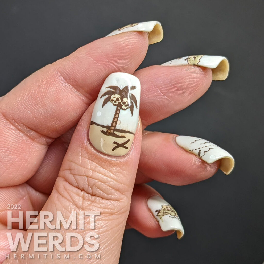 A pale mint green treasure map nail art with reverse stamped islands, monsters, and ships and the final palm tree with 'x' marks the spot.
