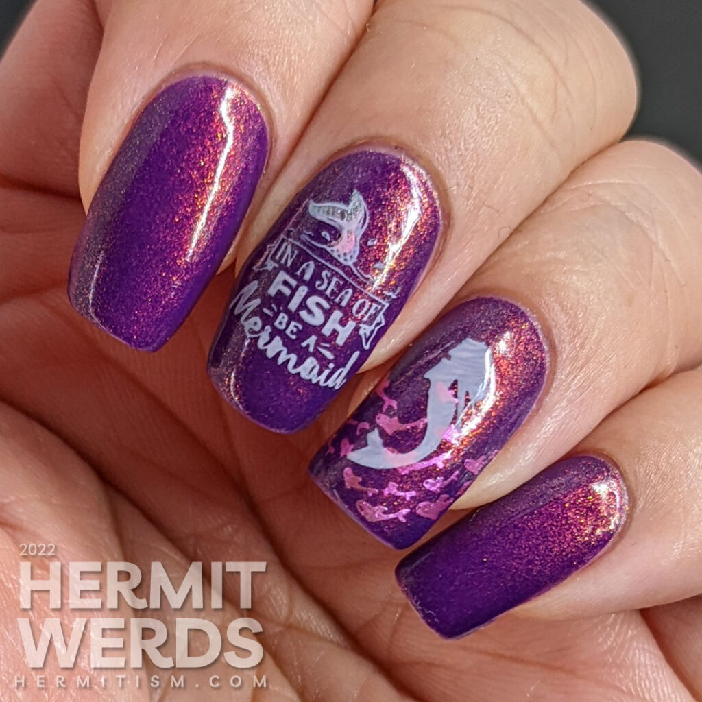 A purple shimmery mermaid nail art that says "In a sea of fish, be a mermaid" with mermaid, mermaid tail, and fish stamping images.