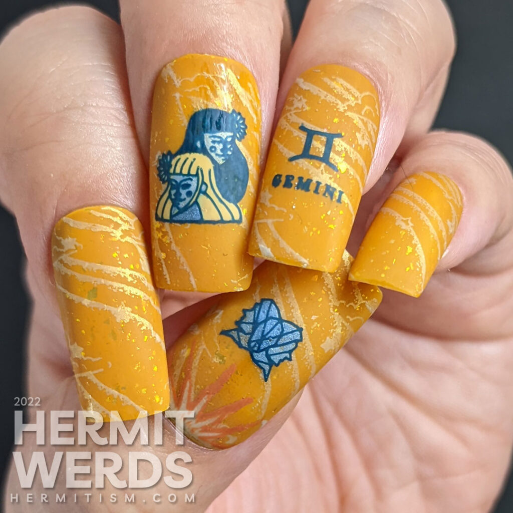 A warm mustard Gemini zodiac nail art with a pair of blue twin stamping decals, Gemini symbols, and a soft windy background stamp.