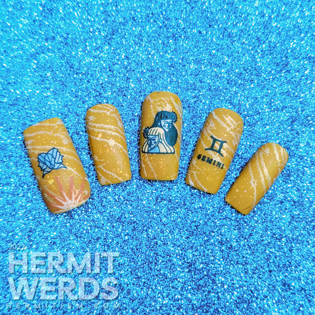 A warm mustard Gemini zodiac nail art with a pair of blue twin stamping decals, Gemini symbols, and a soft windy background stamp.