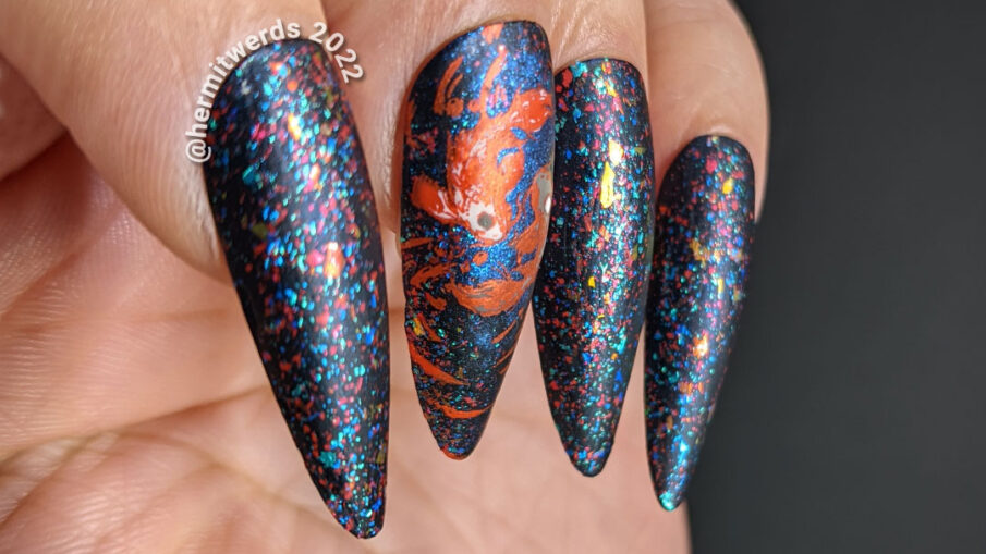 Yin yang nail art w/a koi fish yin yang stamping decal on stiletto shaped false nails covered in red, blue, and green flakies.