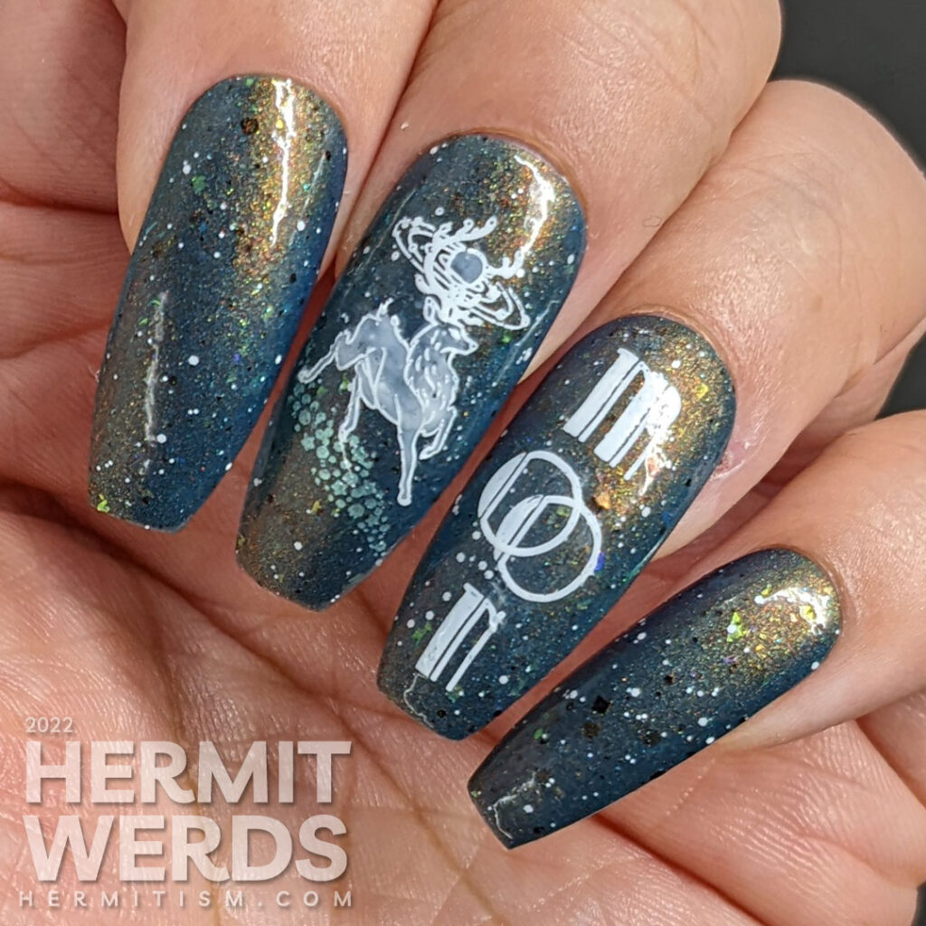 A deep blue and shimmery galaxy nail art celebrating the full buck moon with stamping decals of astral bucks leaping amongst the stars.
