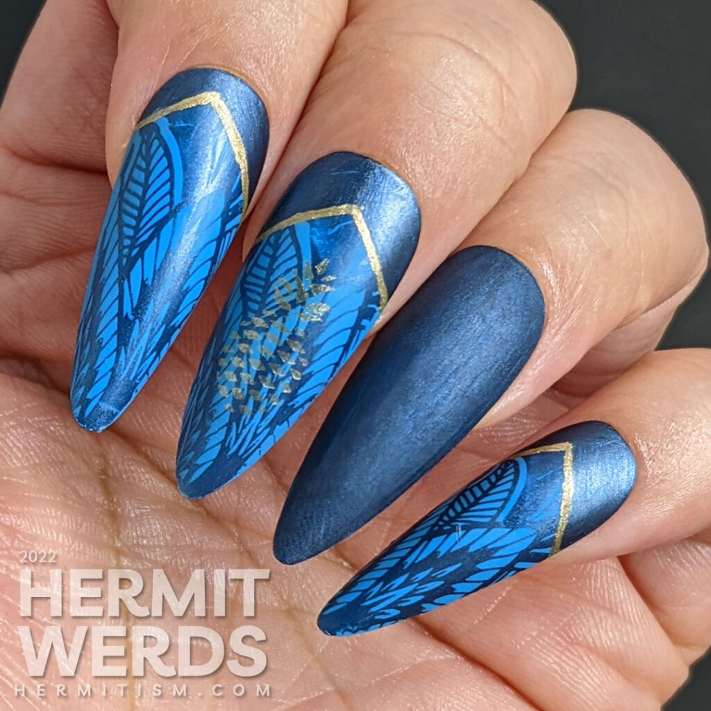 Golden pineapple nail art on blue stiletto falsies with a beautiful art deco lace pattern stamped in the background and half moons.