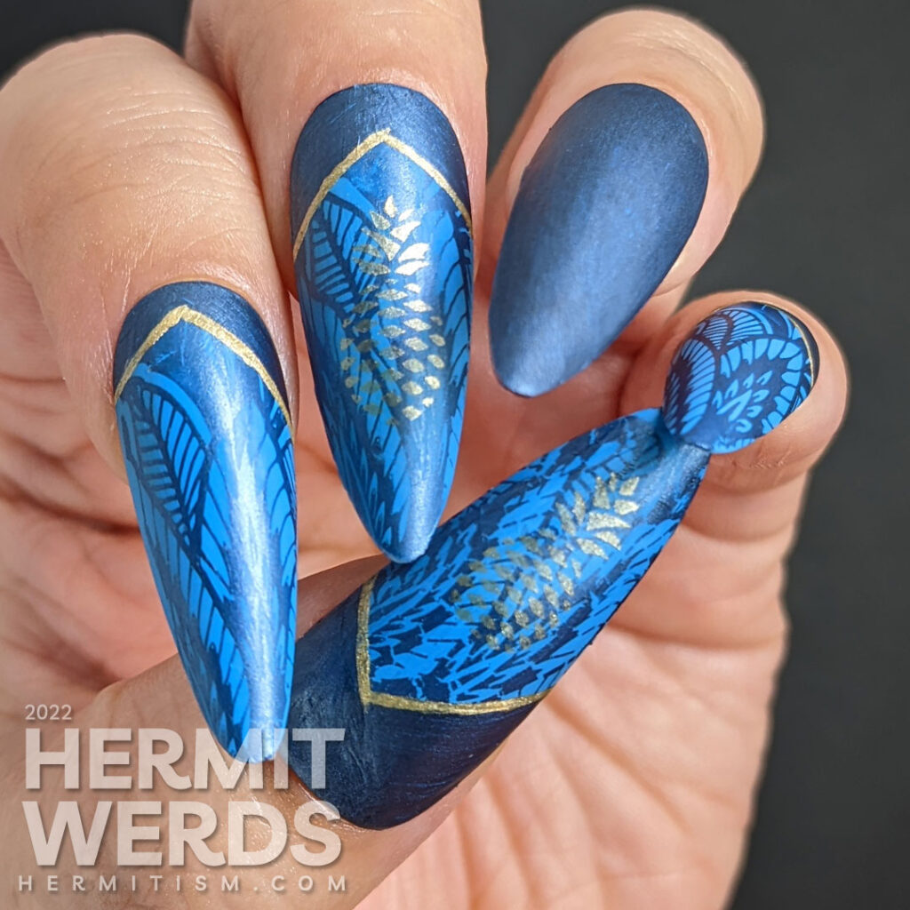 Golden pineapple nail art on blue stiletto falsies with a beautiful art deco lace pattern stamped in the background and half moons.